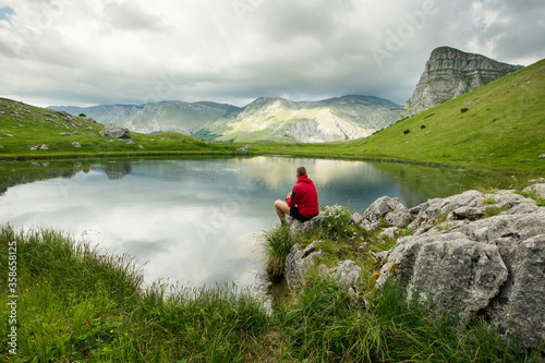 Hiker standing near mountain lake