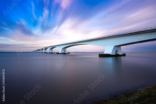 Zeeland Bridge - long white bridge over the river, beautiful blue sky with dynamic clouds. Long time, calm water of the Oosterschelde ..