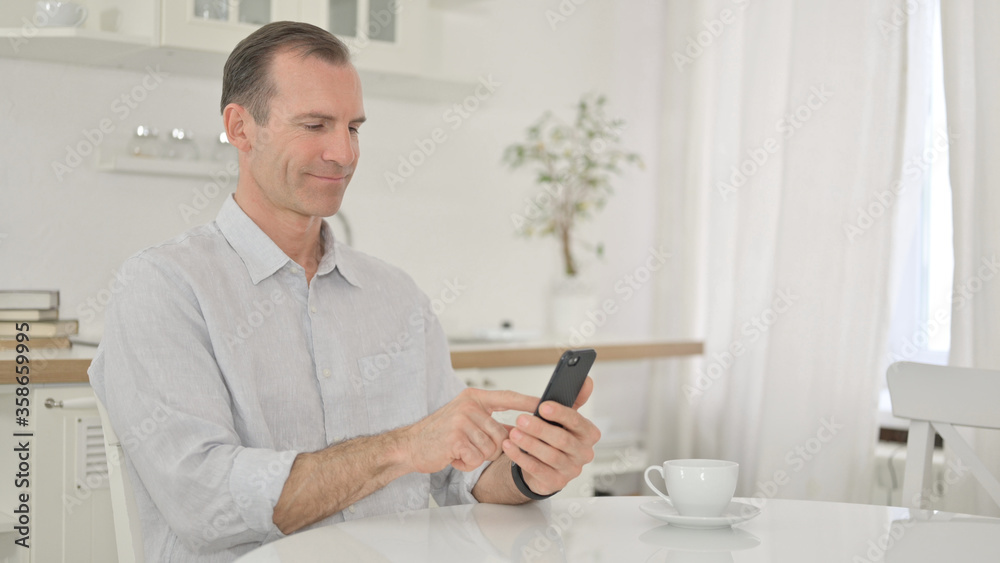 Attractive Middle Aged Man using Smartphone at Home
