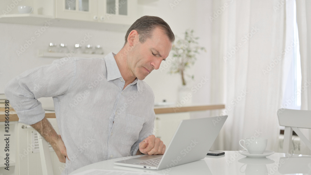 Middle Aged Man with Laptop having Back Pain at Home