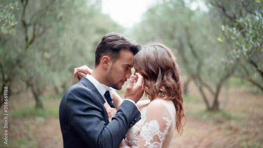 Close-up portrait of pretty woman in lace wedding dress and handsome man in suit looking in each others eyes, hugging and cuddling. Young happy couple in love enjoying each other on background of Close-up portrait of pretty woman in lace wedding dress and handsome man in suit looking in each others eyes, hugging and cuddling. Young happy couple in love enjoying each other on background of