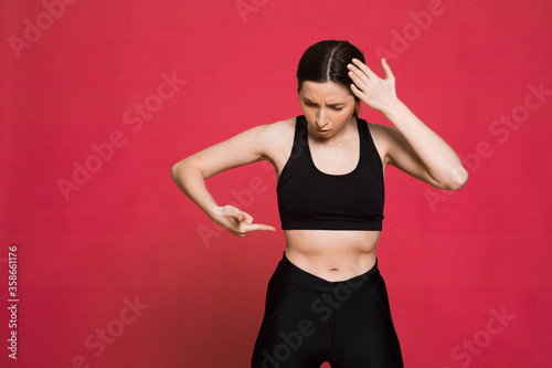 attractive young woman in sportswear stretching muscles before training on red