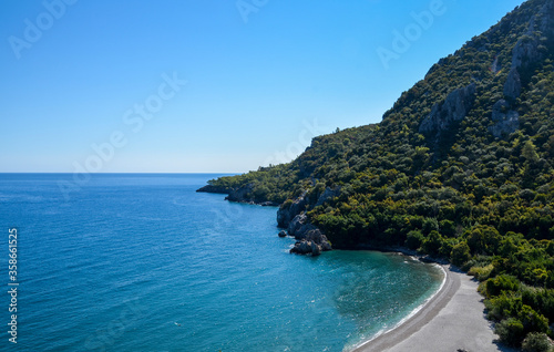 Summer mediterranean coastal landscape. View of Cirali Beach from ancient Olympos ruins, with mountains and pine trees in background Antalya Turkey.
