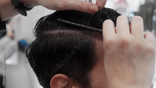 Professional female hairstylist combing man hair