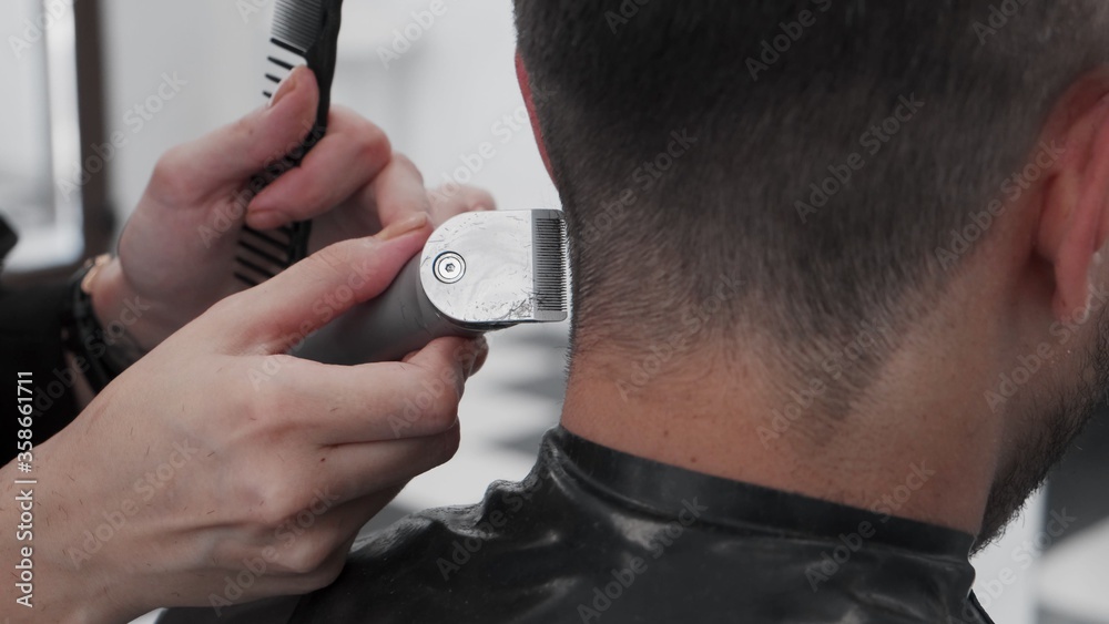 Fototapeta premium Cutting man hair with trimmer in salon