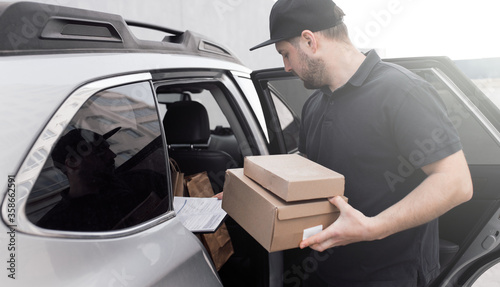 Smiling delivery man standing in front of his vehicle