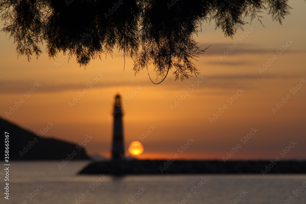 Seascape at sunset. Lighthouse on the coast. Seaside town of Turgutreis and spectacular sunsets