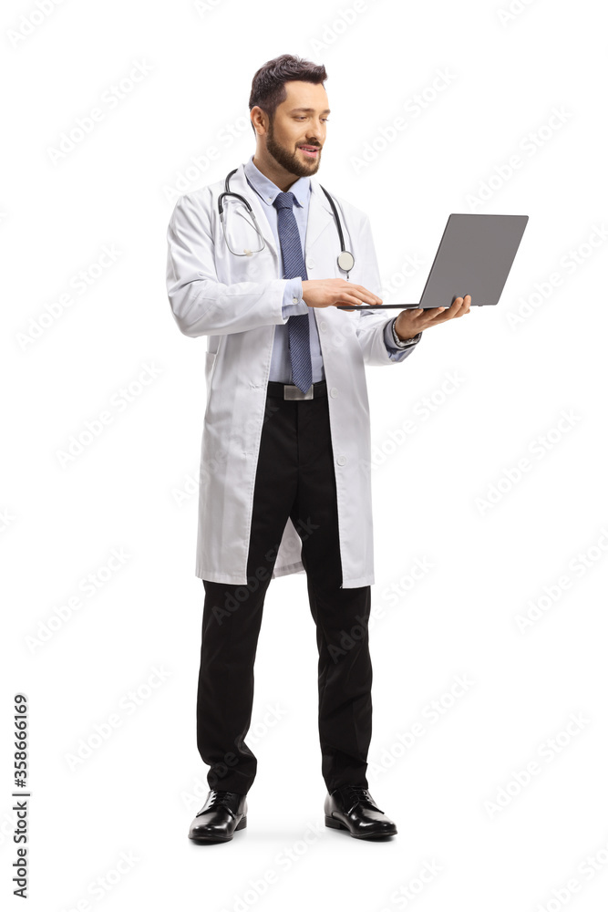 Full length portrait of a male doctor standing and working on a laptop computer
