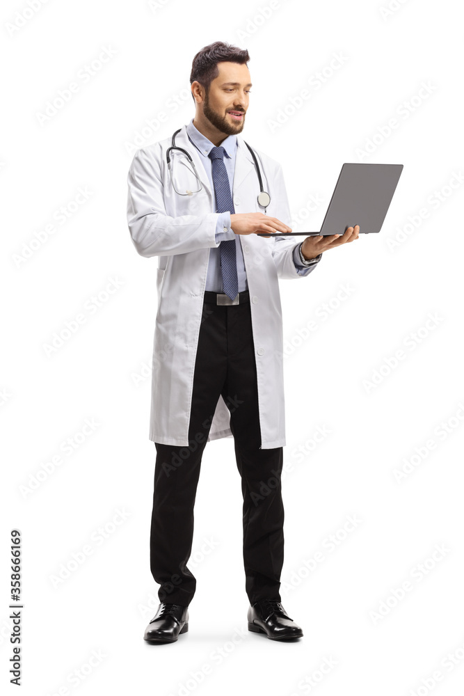 Full length portrait of a male doctor standing and working on a laptop computer Full length portrait of a male doctor standing and working on a laptop computer