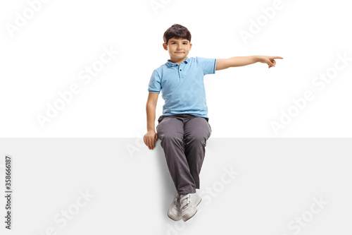 Child sitting on a blank panel and pointing to the side