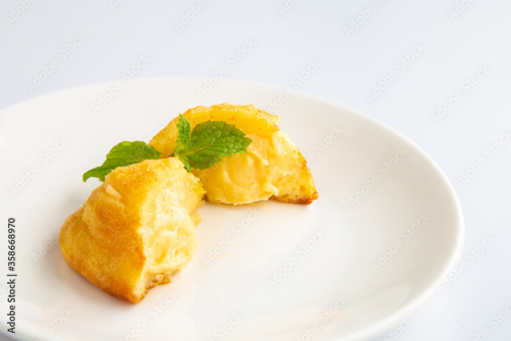 Close up a group of homemade Choux (Eclair) in a white dish on a white table Close up a group of homemade Choux (Eclair) in a white dish on a white table