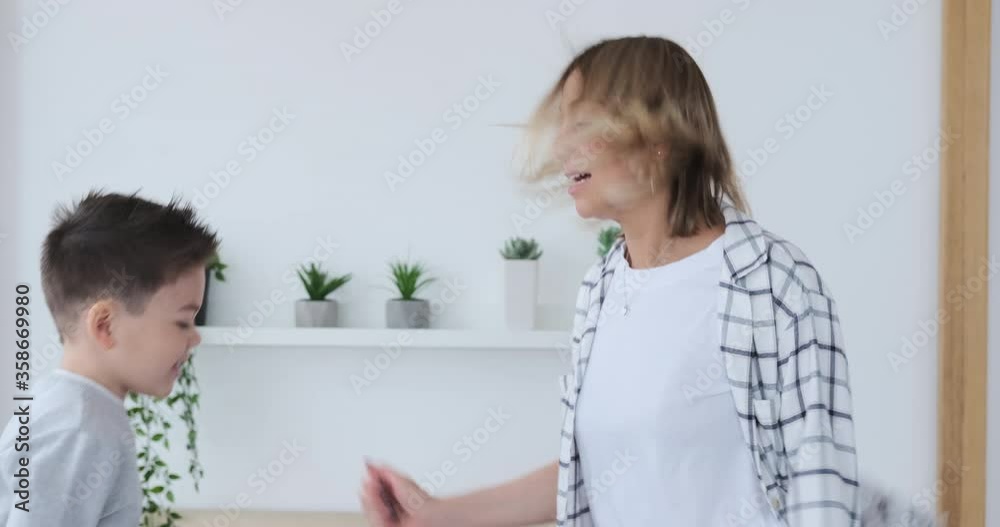 Excited mother with son having fun jumping together on bed at home Excited mother with son having fun jumping together on bed at home