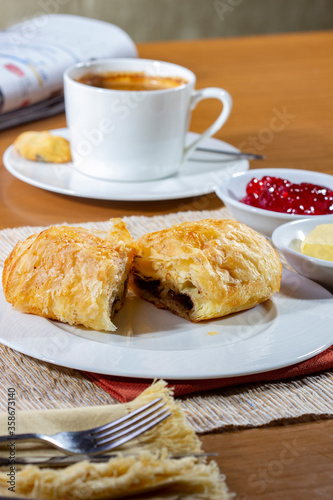 Breakfast with Croissants and a cup of coffee, accompanied by a newspaper. Croissants with strawberry jam and butter.