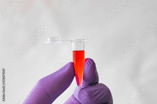 Red sample in a 1.5 ml microcentrifuge tube in gloved hand