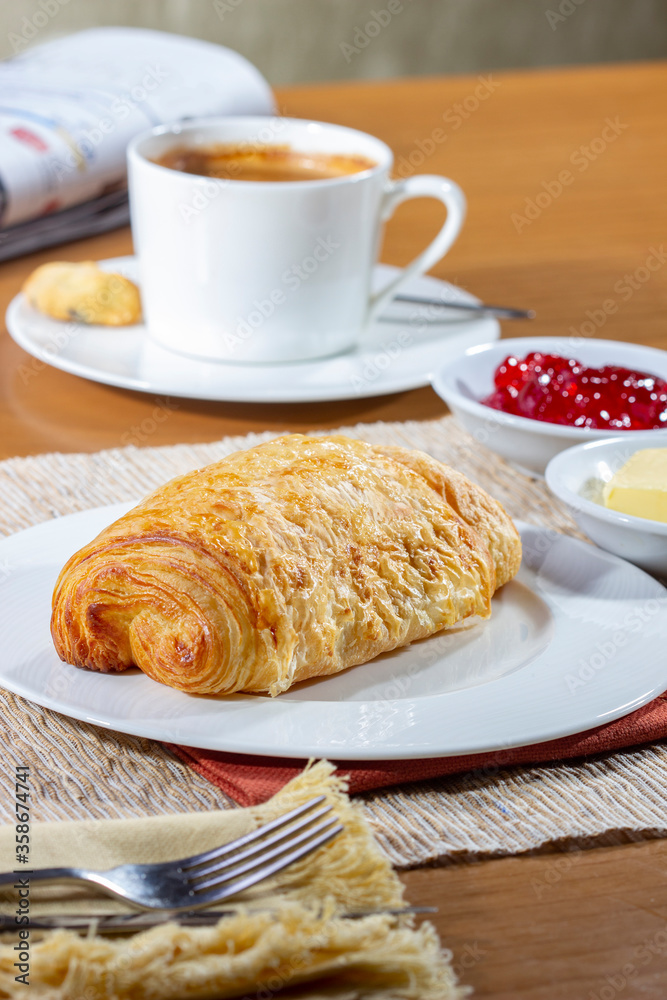 Breakfast with Croissants and a cup of coffee, accompanied by a newspaper. Croissants with strawberry jam and butter. Breakfast with Croissants and a cup of coffee, accompanied by a newspaper. Croissants with strawberry jam and butter.