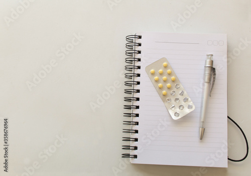 Yellow pills, notebook and pen, remember concept photo
