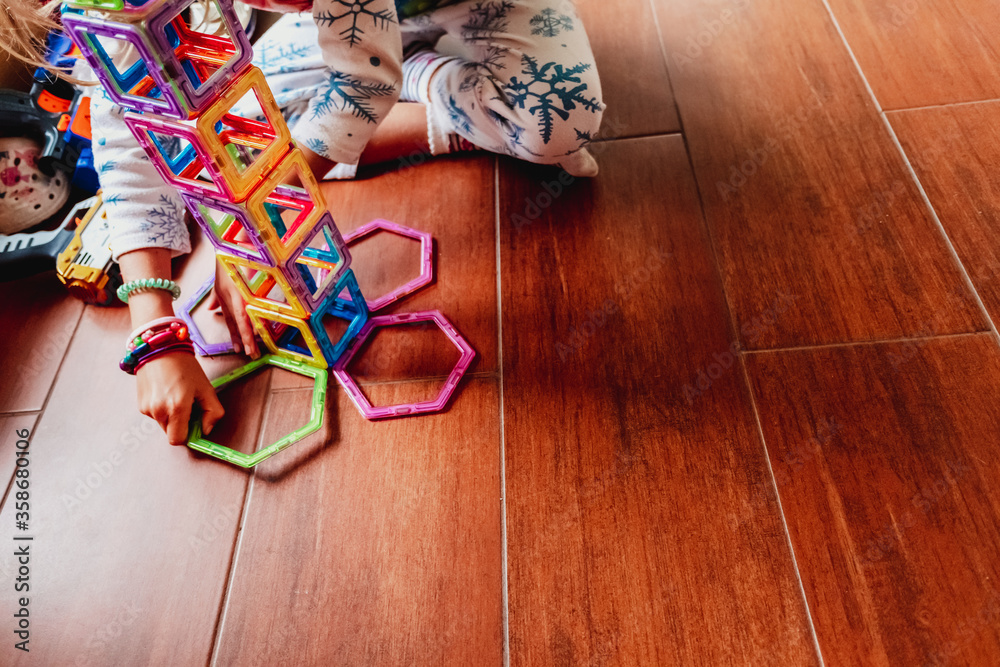 Child playing with building blocks to learn motor and social skills.