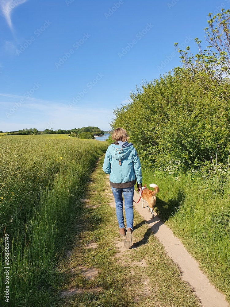 Junge Frau spaziert mit dem Hund an der Küste von Schleswig - Holstein