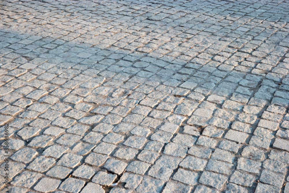 Pavement of gray square stones with shadows