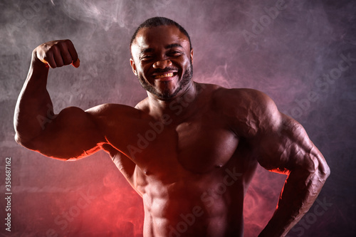 Close up of a bodybuilder. African American male athlete posing demonstrating muscular development of biceps arm