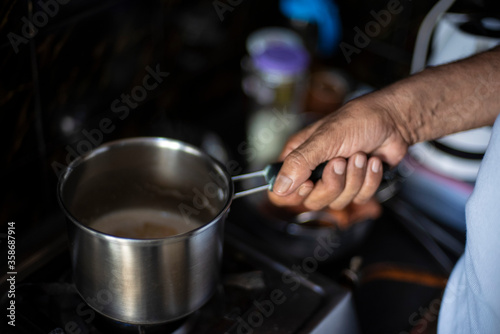 Tea being prepared in a steel tea pot in an Indian kitchen. Indian drink and beverages.