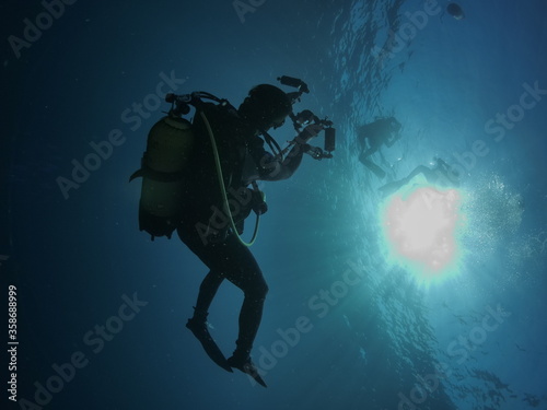 photographer underwater scuba diver with sun beams sun rays and sun shine underwater silhouette man in ocean scenery © underocean
