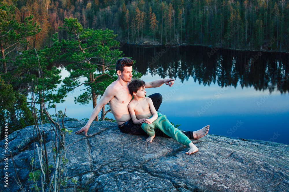 Fototapeta premium middle age man with little cute son doing sport yoga on the top of the mountain together, happy family lifestyle people outdoor, summer wild nature for training