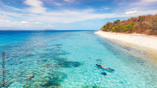 Aerial drone view of an empty white sandy beach with a man snorkeling in tropical Moyo Island, Sumbawa, Indonesia photo