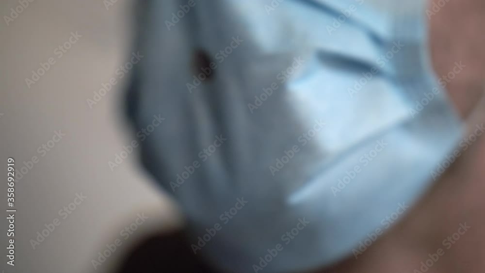 A man leaning forward while smoking through a hole in a face mask