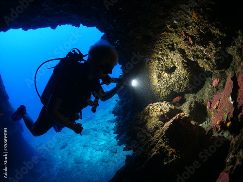 cave diving underwater scuba divers exploring caves ocean scenery sun beams and rays background © underocean