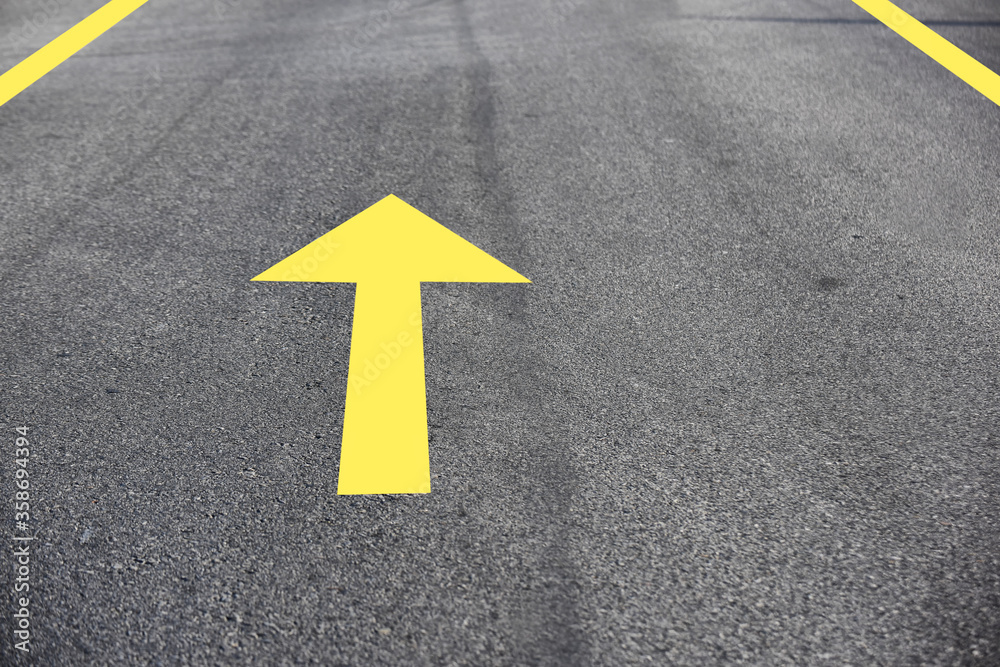 Yellow arrow on asphalt road surface, transportation concept and keep moving idea