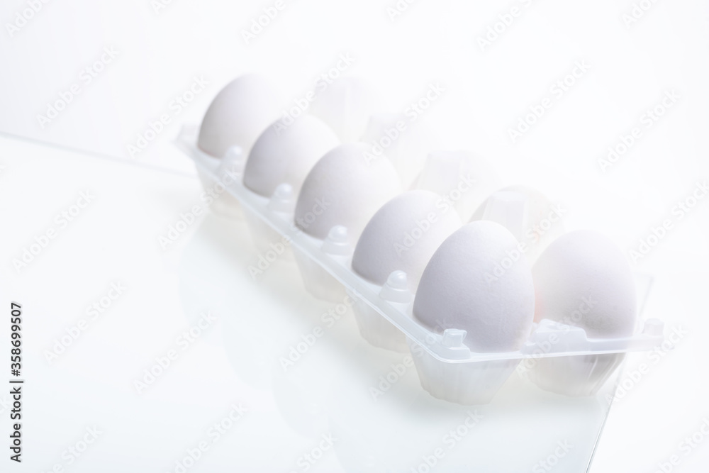 packaging with fresh white chicken eggs on glass isolated on white background