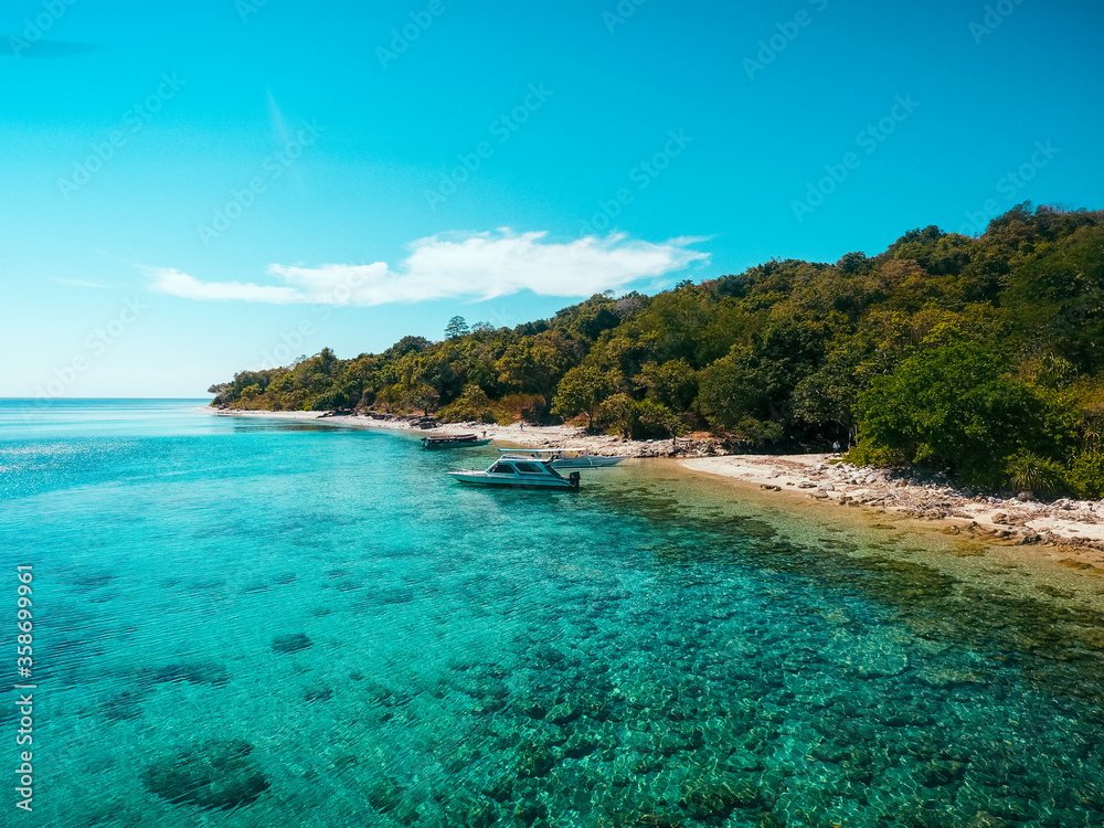 Aerial drone view of an empty white sandy beach with boat in tropical Moyo Island, Sumbawa, Indonesia