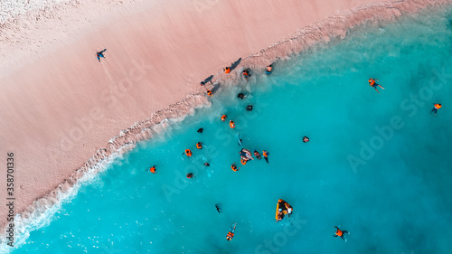 People swimming and playing on the beach. Tourists on the Pink Beach, Labuan Bajo, Indonesia. A bird eye view photo captured with drone.