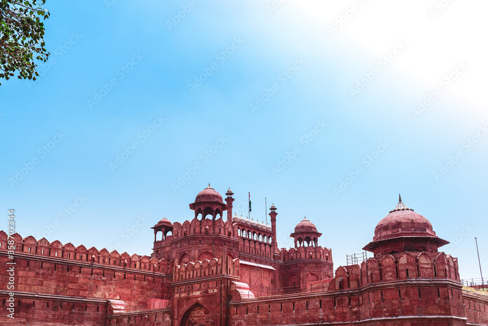 A huge fortress of Mughal empire in India with high walls on a sunny summer afternoon. Red fort of Delhi, a famous historic travel destination isolated in clear blue sky background with copy space.