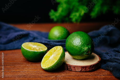 fresh limes with slice and leaves on dark background 