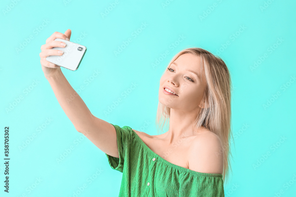 Portrait of beautiful young woman taking selfie on color background Portrait of beautiful young woman taking selfie on color background