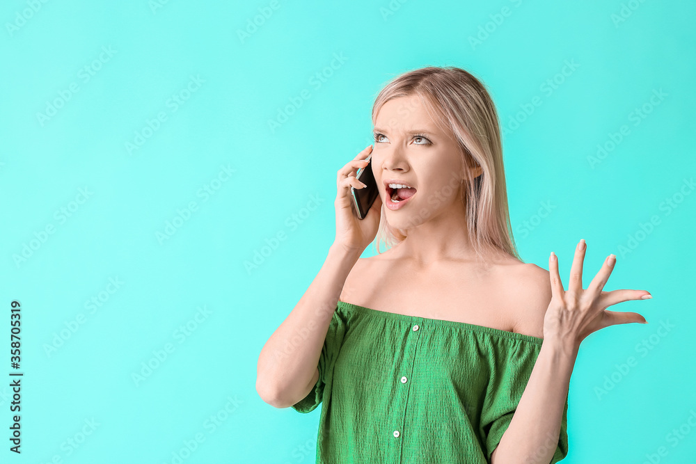 Portrait of angry young woman talking by phone on color background Portrait of angry young woman talking by phone on color background