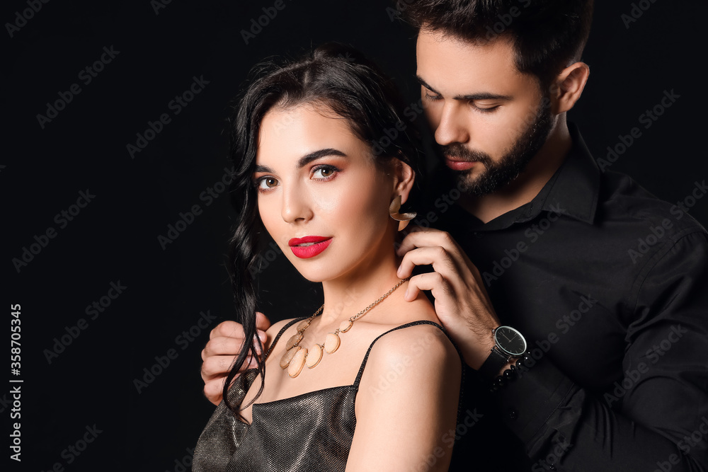 Young couple wearing stylish accessories on dark background Young couple wearing stylish accessories on dark background