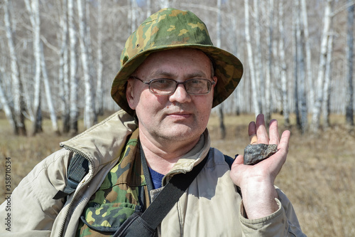 Canvas Print a man holds in his hand a fragment of the Chelyabinsk meteorite found in the for