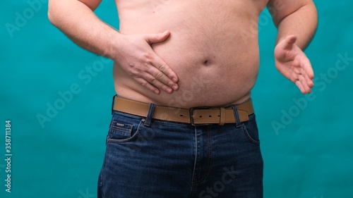 male with a big belly shows his fat on a green screen. The concept of healthy eating and losing weight, diet