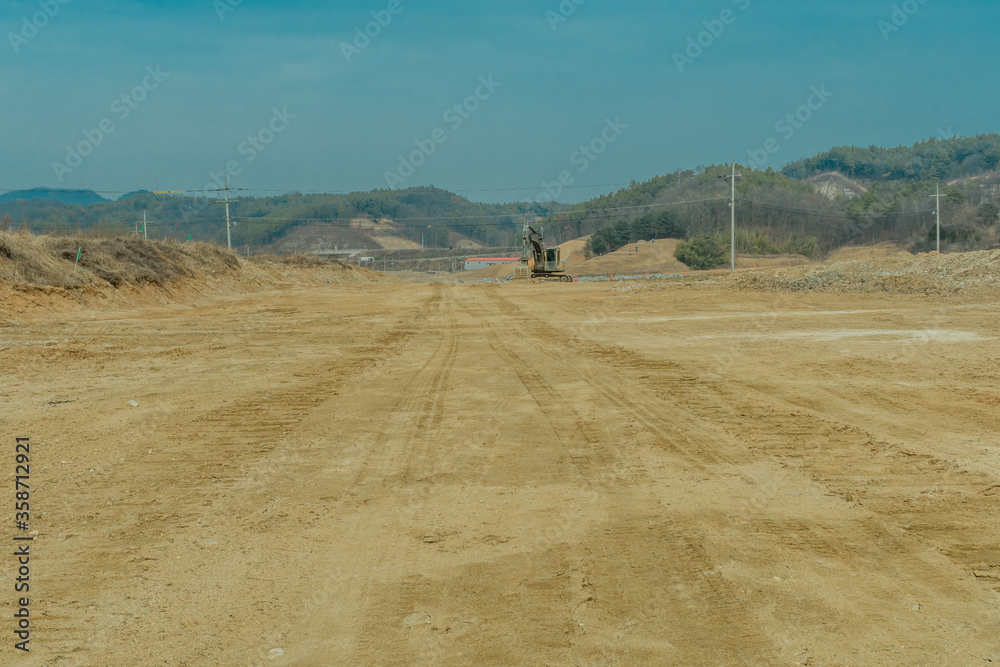 Obraz premium Backhoe tracks running across dirt in field of new construction project.