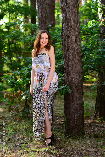 Beautiful young smiling woman posing in long dress outdoor