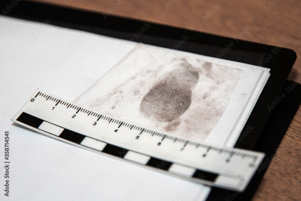 paper ruler and fingerprint on a sheet in the office of the investigator. Fingerprint police uniforms. Forensic-medical examination