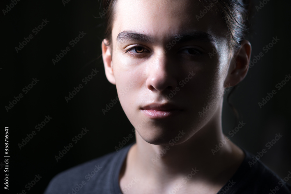 Portrait of young man with long hair in low key with Rembrandt lightning Portrait of young man with long hair in low key with Rembrandt lightning