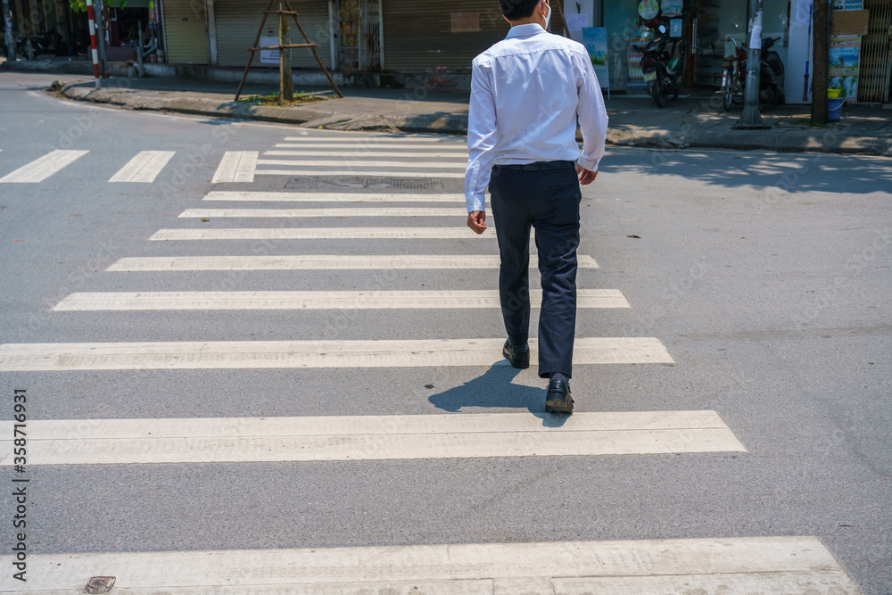 Asian man walking on street on crosswalk sign