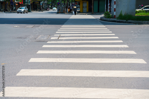 Crosswalk with Vietnamese woman with conical hat walking on background in Hanoi