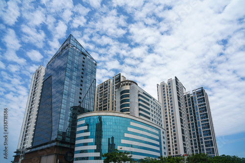 Closeup of top modern high-rise modern buildings. Mirroring of concrete skyscrapers on blue sky in shiny glass windows. © Hanoi Photography
