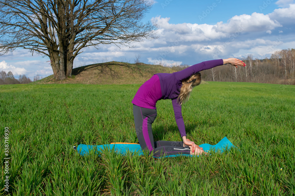 A middle-aged blonde woman practices yoga in nature. Healthy lifestyle. Body concentration. A middle-aged blonde woman practices yoga in nature. Healthy lifestyle. Body concentration.
