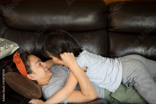 Asian mother and daughter hugging on sofa